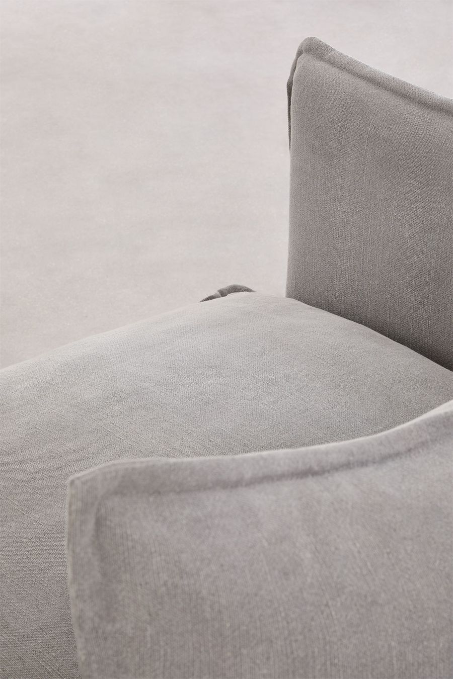 Gros plan sur l'angle de l'accoudoir et de l'assise du canapé Grace en tissu gris.