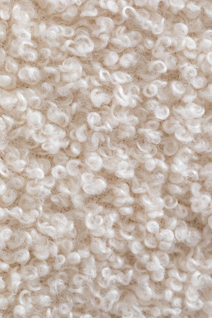 Gros plan d'un tissu bouclé beige clair aux boucles en forme de spirales serrées.