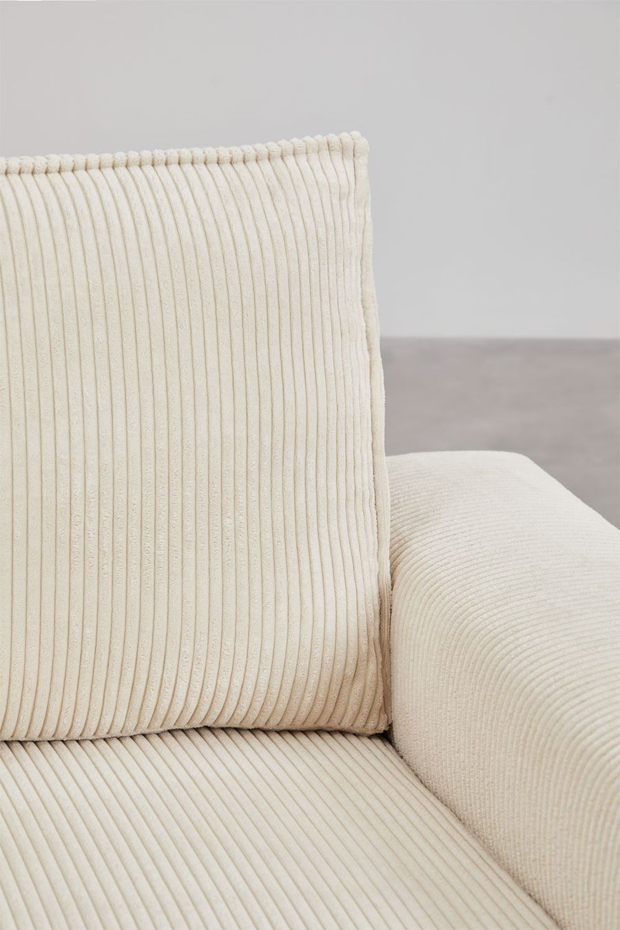 Gros plan du dossier et de l'accoudoir du canapé Tampere en velours côtelé beige crème.