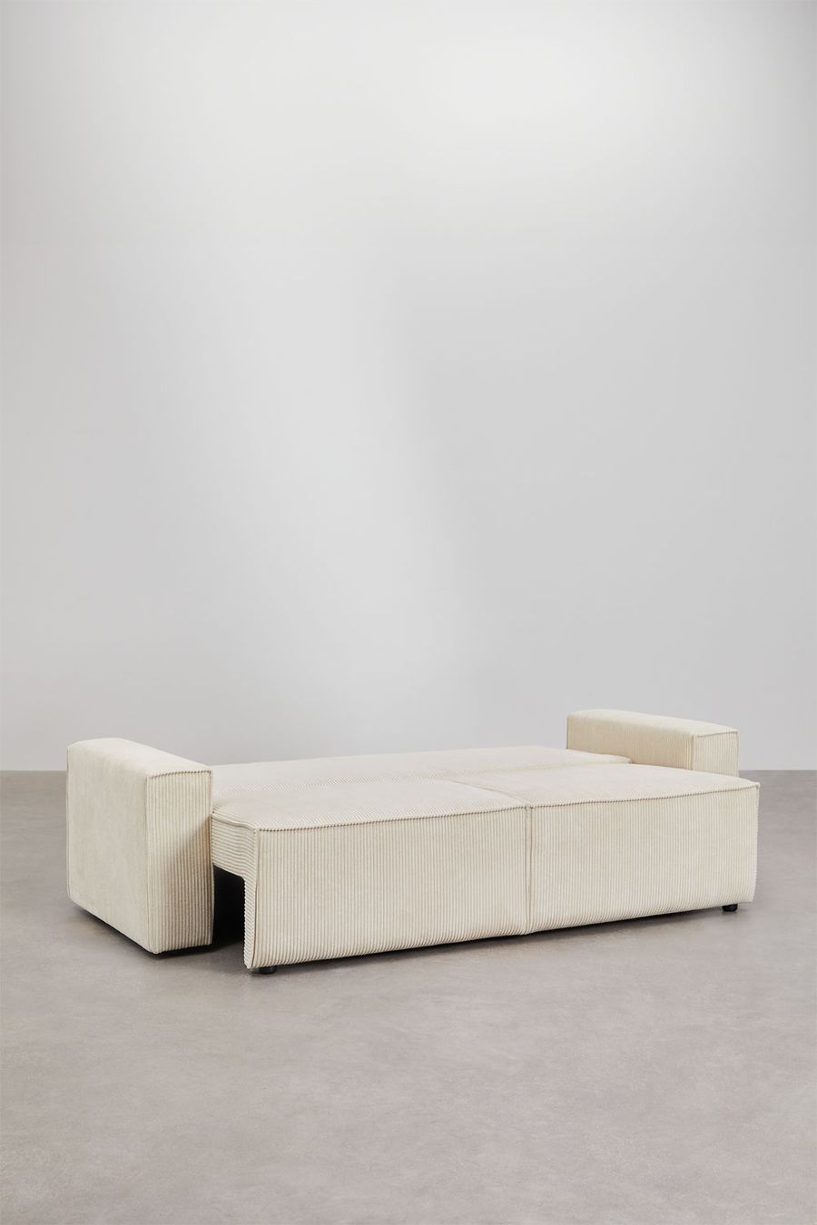 Canapé Tampere déplié vu de dos, assise tirée en couchage beige crème sur fond gris.