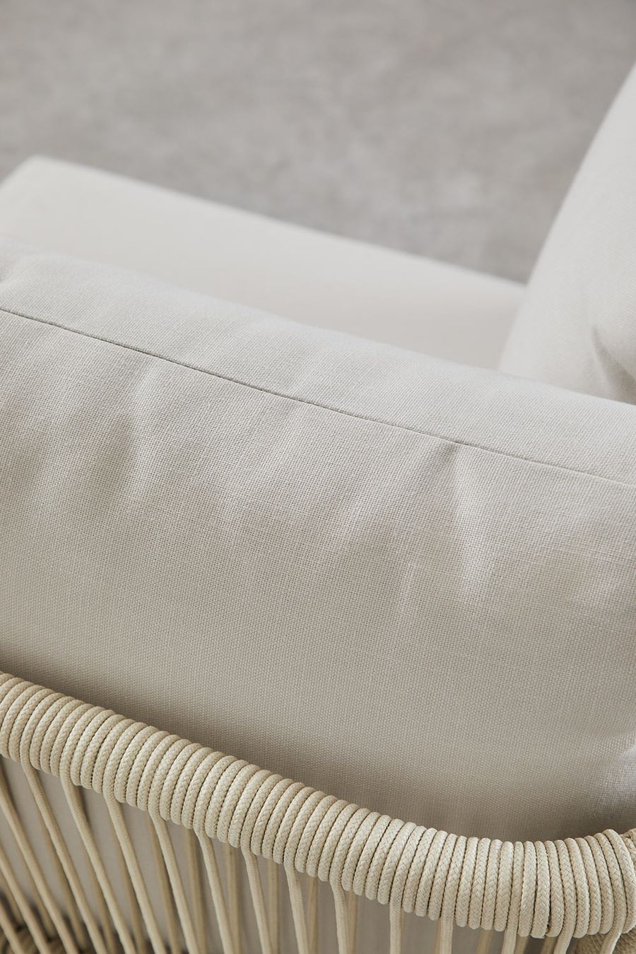 Gros plan du tissu écru d'un coussin et du cordage tressé de l'accoudoir du canapé Dailin.