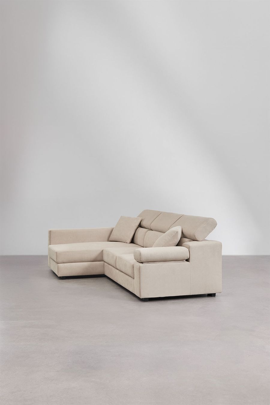 Canapé Aramis beige d'angle vu de trois quarts, appuis-têtes relevés, sol gris.
