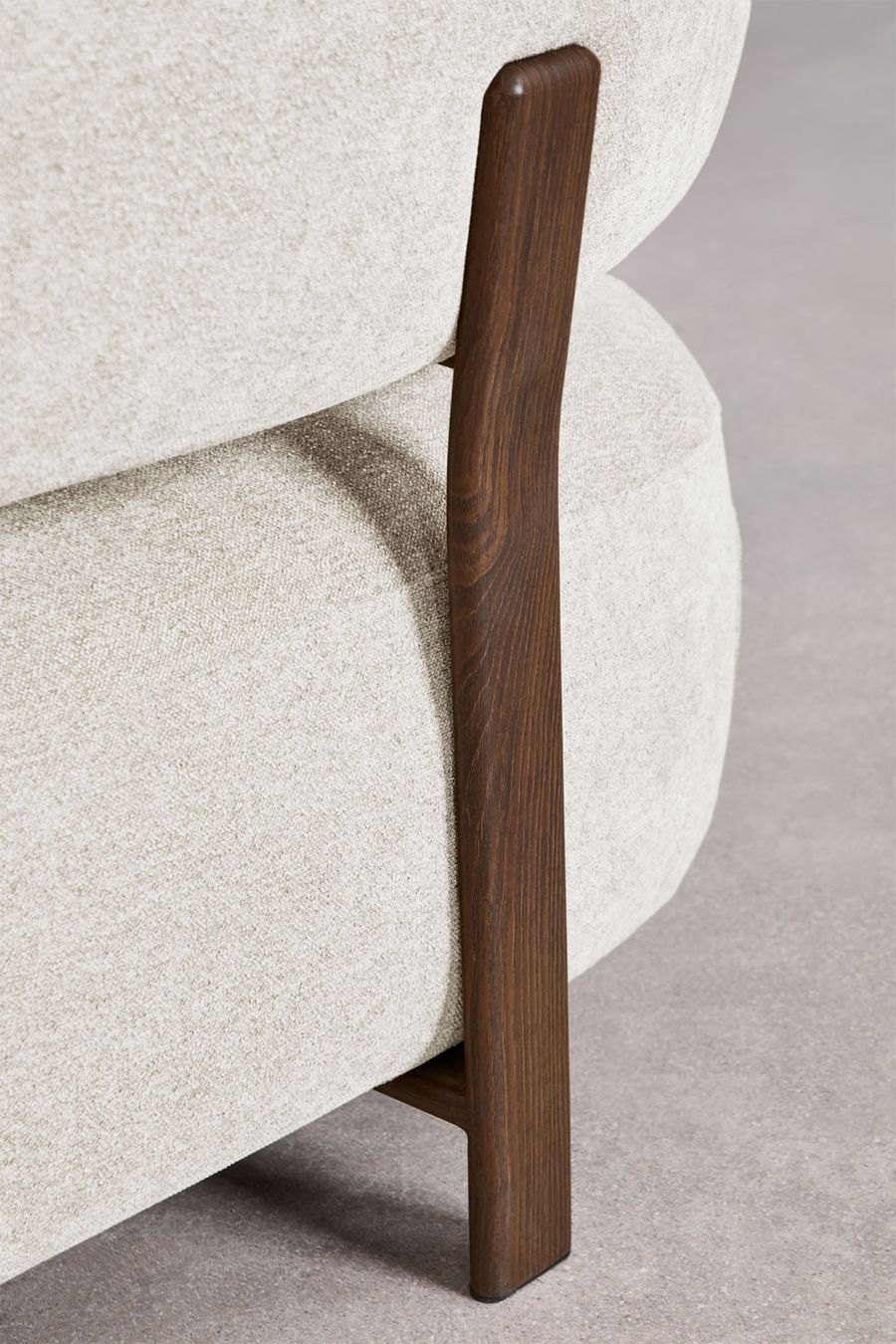 Gros plan d'un montant en bois foncé fixé contre l'assise en tissu crème du canapé Jolie.