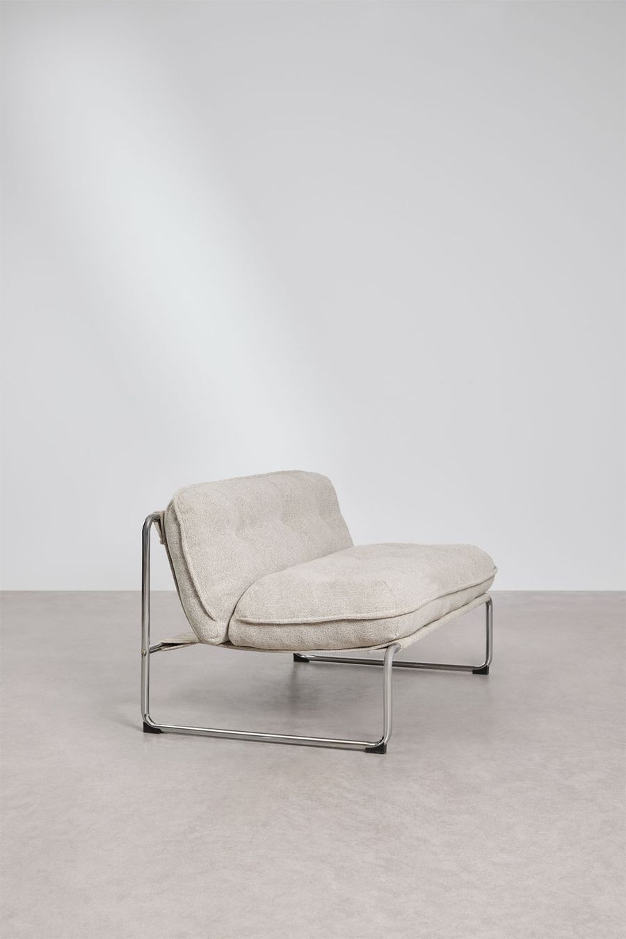 Fauteuil Matilda 1 place en bouclé beige vu de trois quarts sur sol béton, fond gris clair.