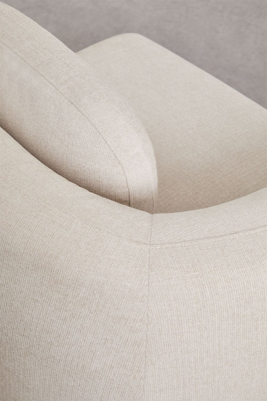 Gros plan d'un accoudoir arrondi du canapé Coquette en tissu beige chiné.