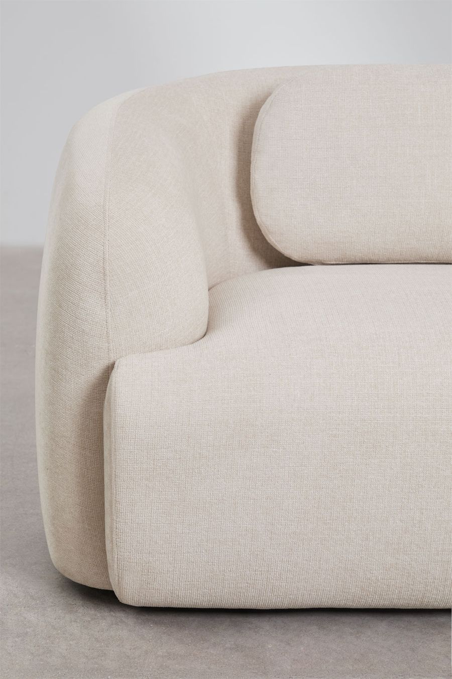 Gros plan de l'accoudoir et du dossier du module d'angle Coquette en tissu beige.