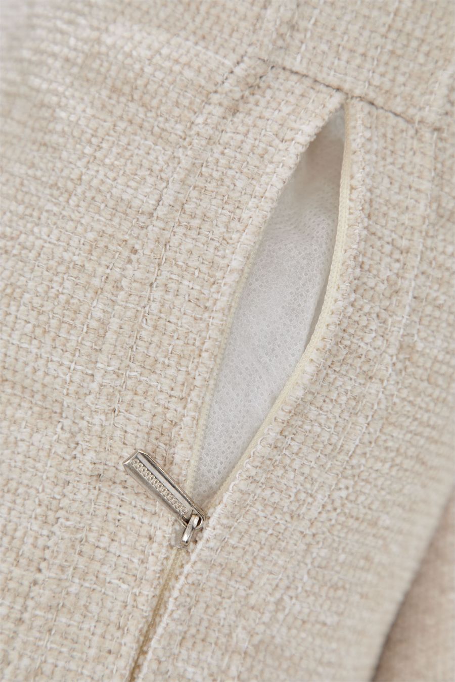 Gros plan d'une poche zippée sur un tissu beige tressé, avec curseur métallique.