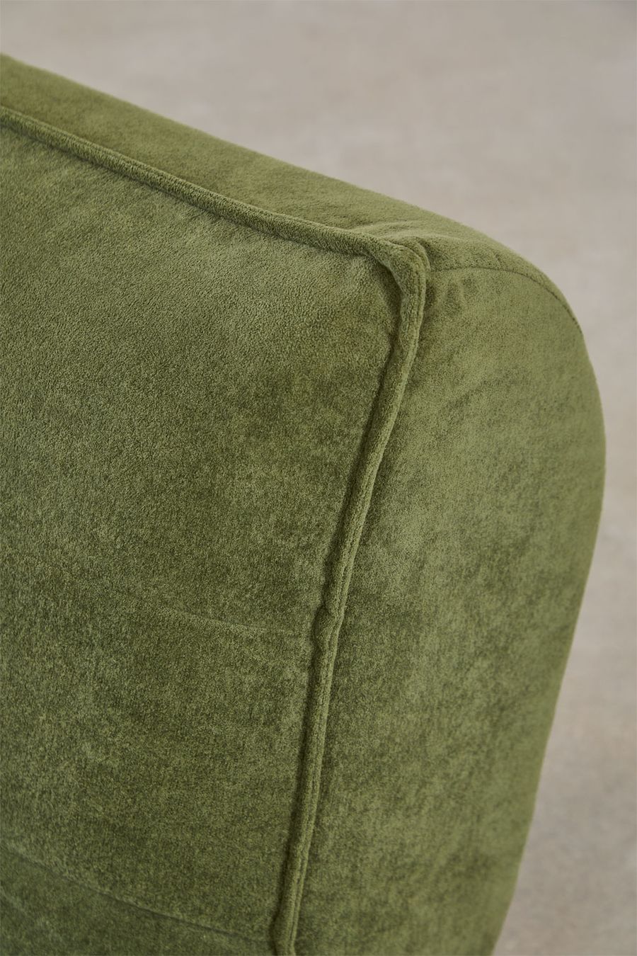 Gros plan de l'accoudoir arrondi du canapé Mati en tissu vert côtelé.