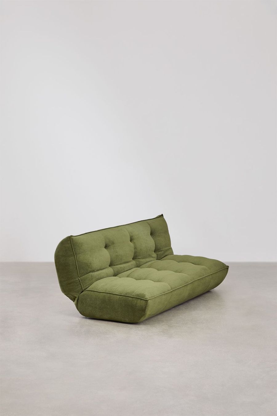 Canapé Mati vert olive vu de trois quarts sur sol béton, dossier et assise visibles.