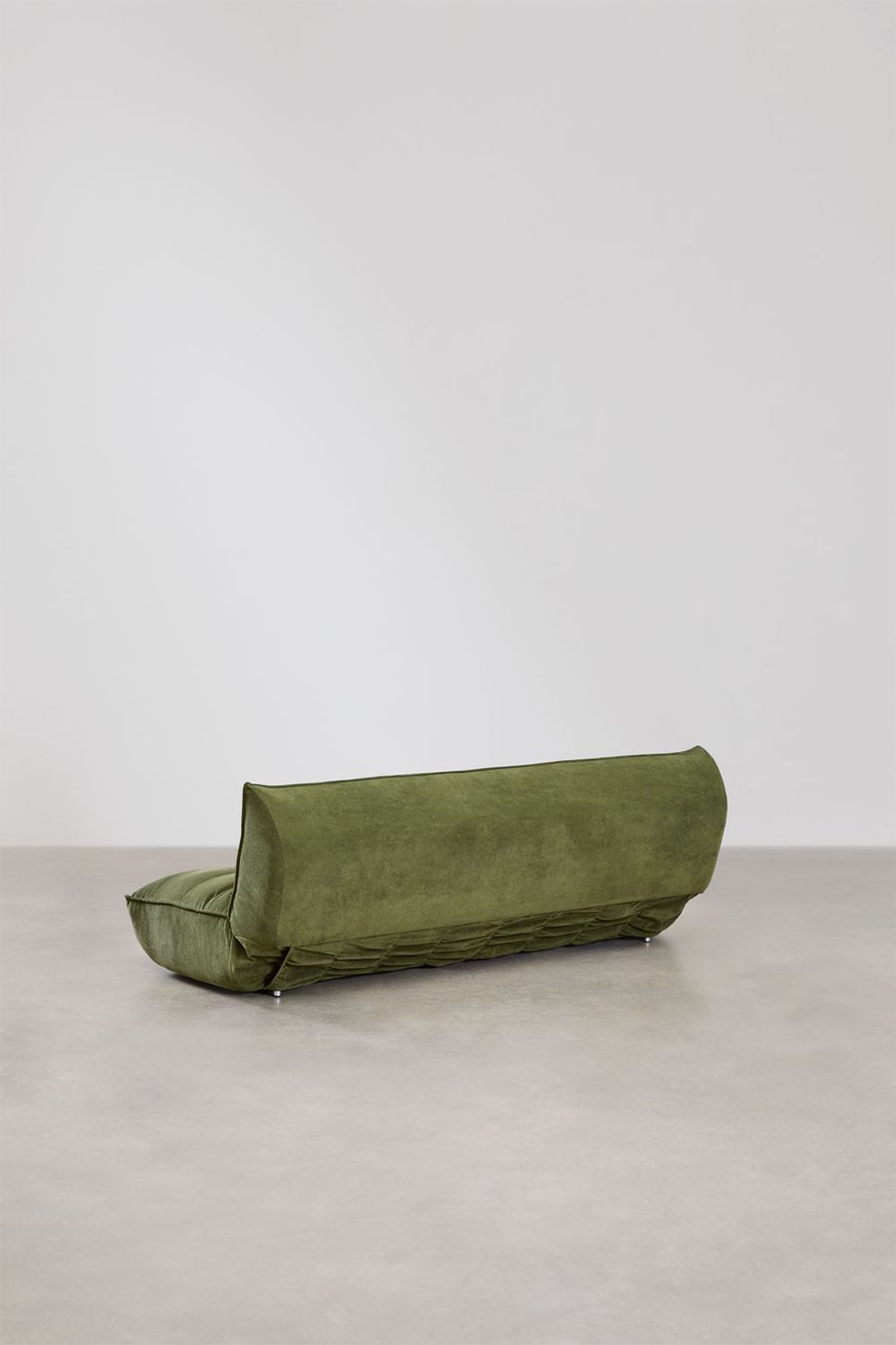 Canapé Mati vu de dos, base en tissu matelassé vert sur sol béton.