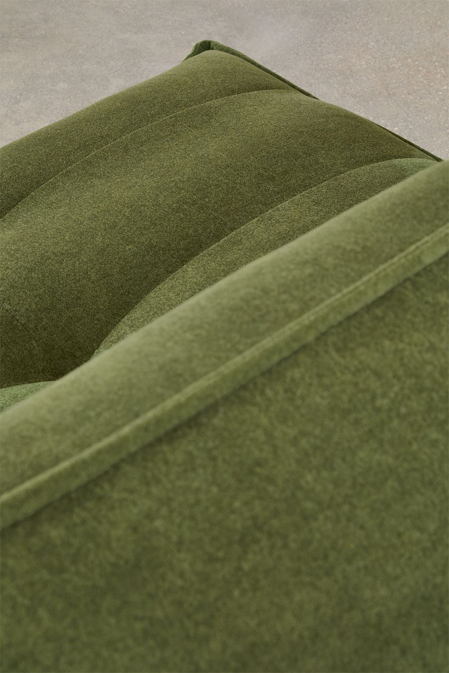 Gros plan des coussins matelassés et de la couture du canapé Mati vert.