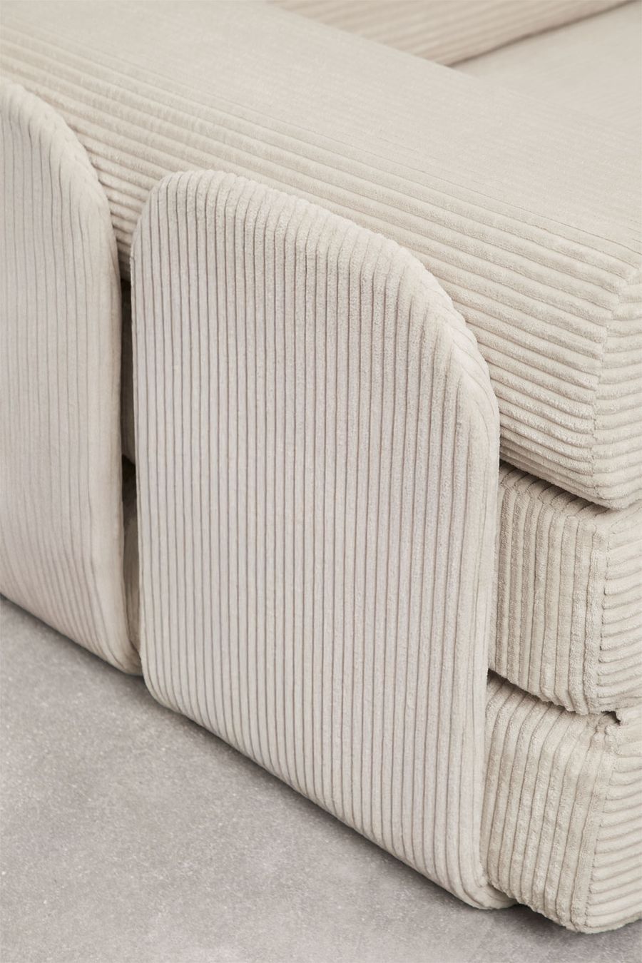 Gros plan des modules d'accoudoir arrondis du canapé Paoly en velours côtelé beige, de profil.