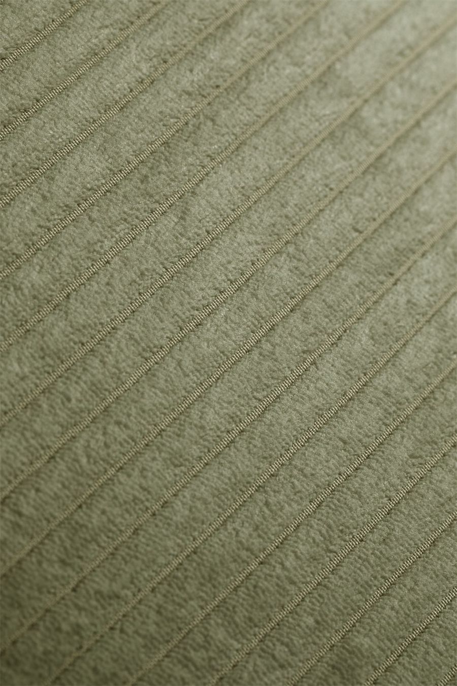 Gros plan du velours côtelé vert montrant la texture et les côtes du tissu.