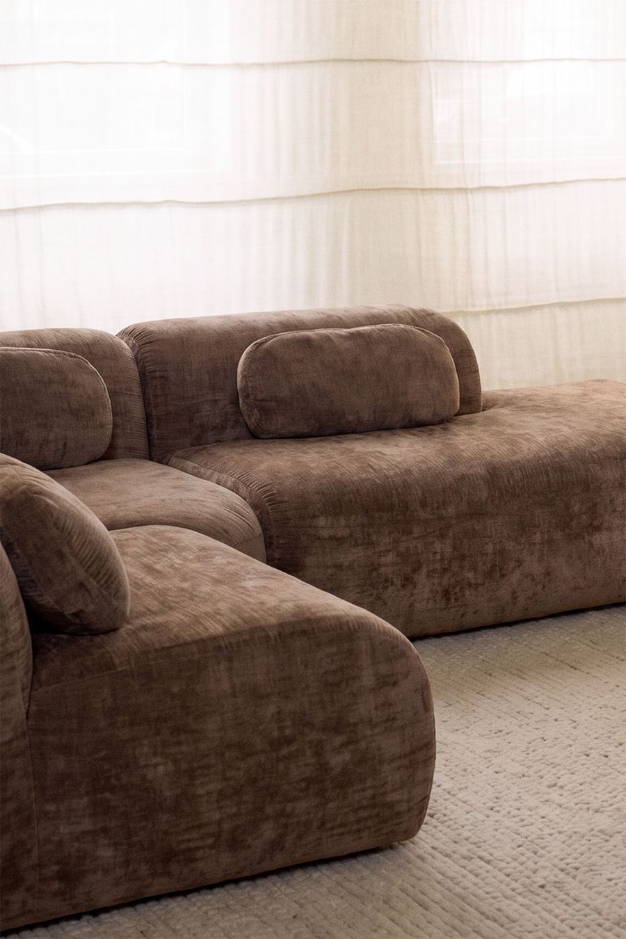 Gros plan sur les modules du canapé Merida brun et son coussin cylindrique sur le dossier.