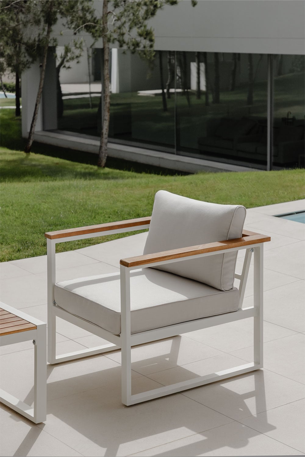 Sillón de exterior con estructura blanca y cojines beige